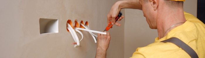 Electrician works with electric wires in new apartment.